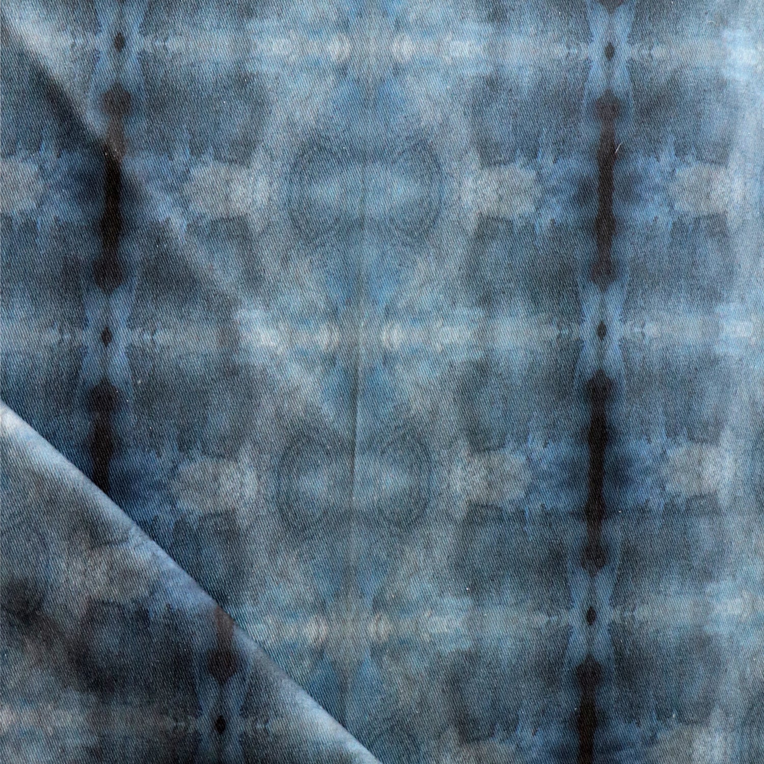 Detail of draped fabric in a repeating ink blot print in navy on a charcoal field.