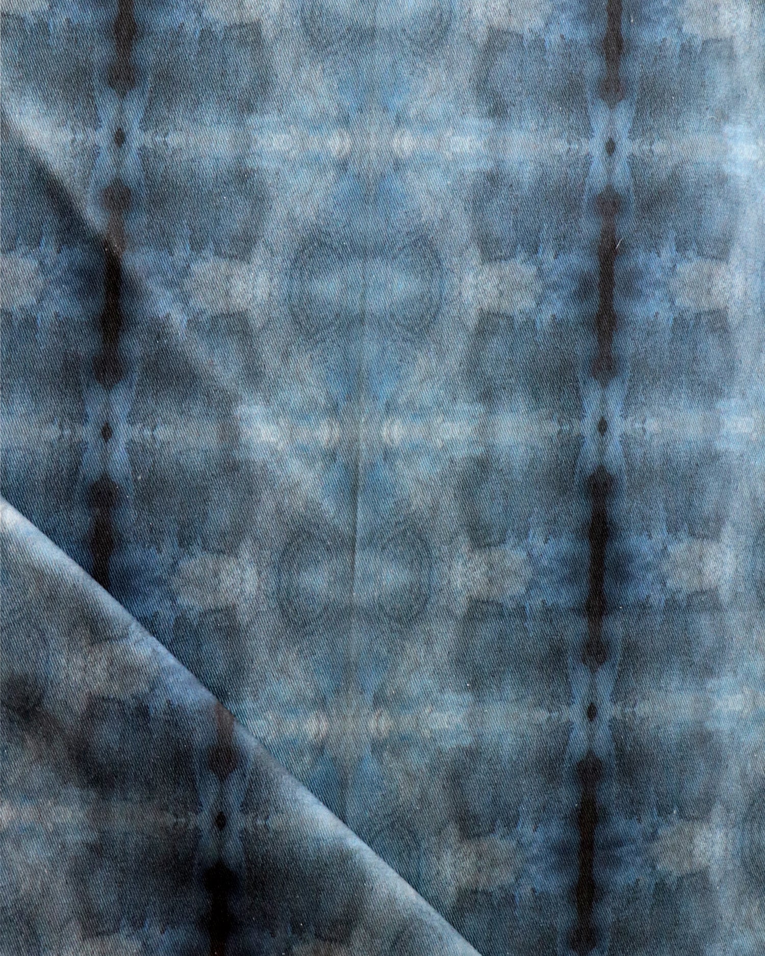 Detail of draped fabric in a repeating ink blot print in navy on a charcoal field.