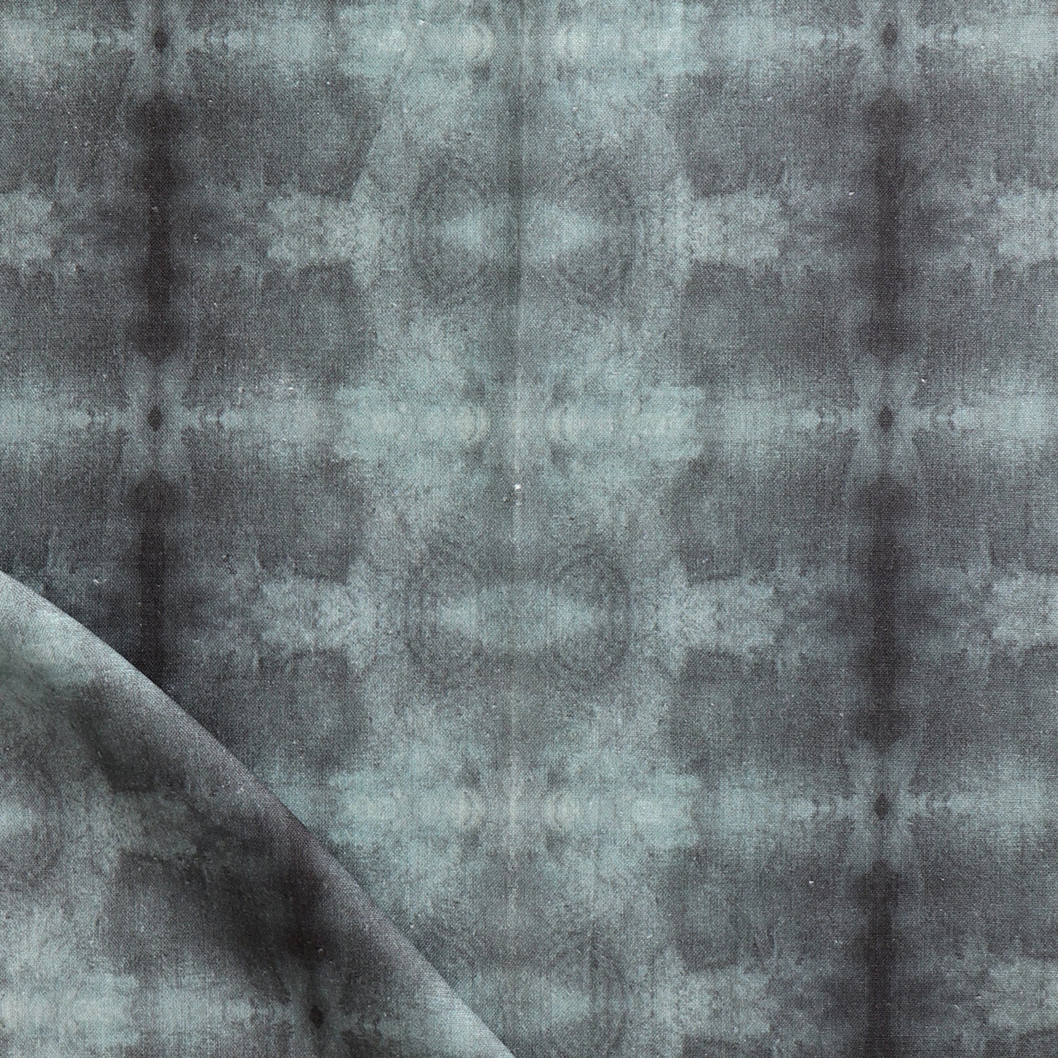Detail of draped fabric in a repeating ink blot print in shades of gray.