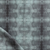 Detail of draped fabric in a repeating ink blot print in shades of gray.
