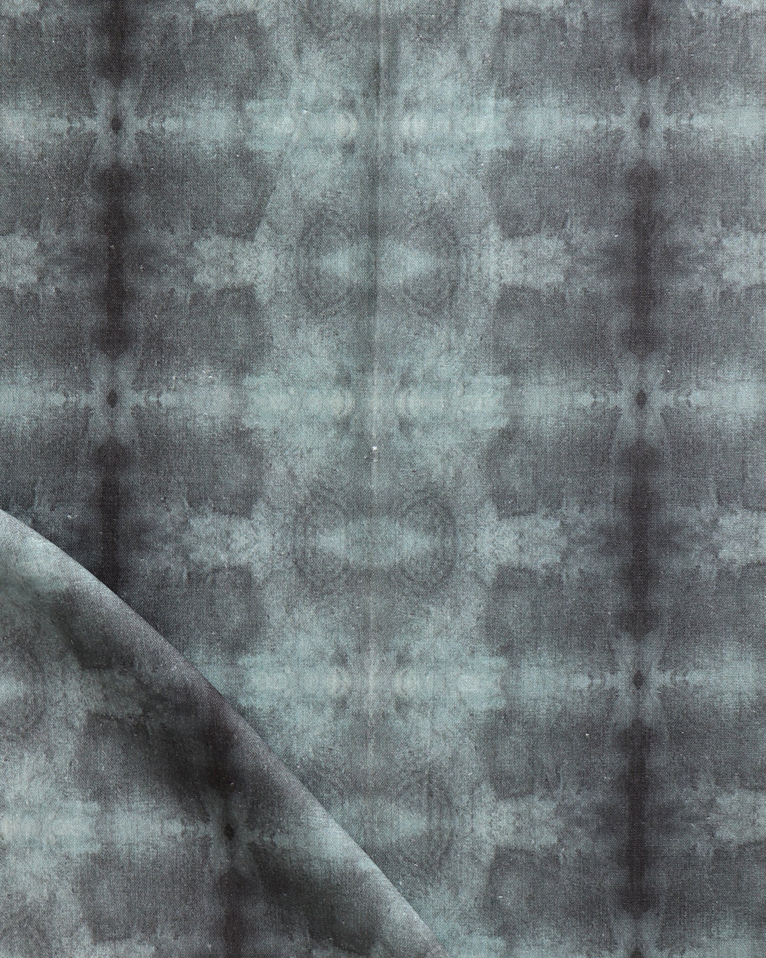 Detail of draped fabric in a repeating ink blot print in shades of gray.
