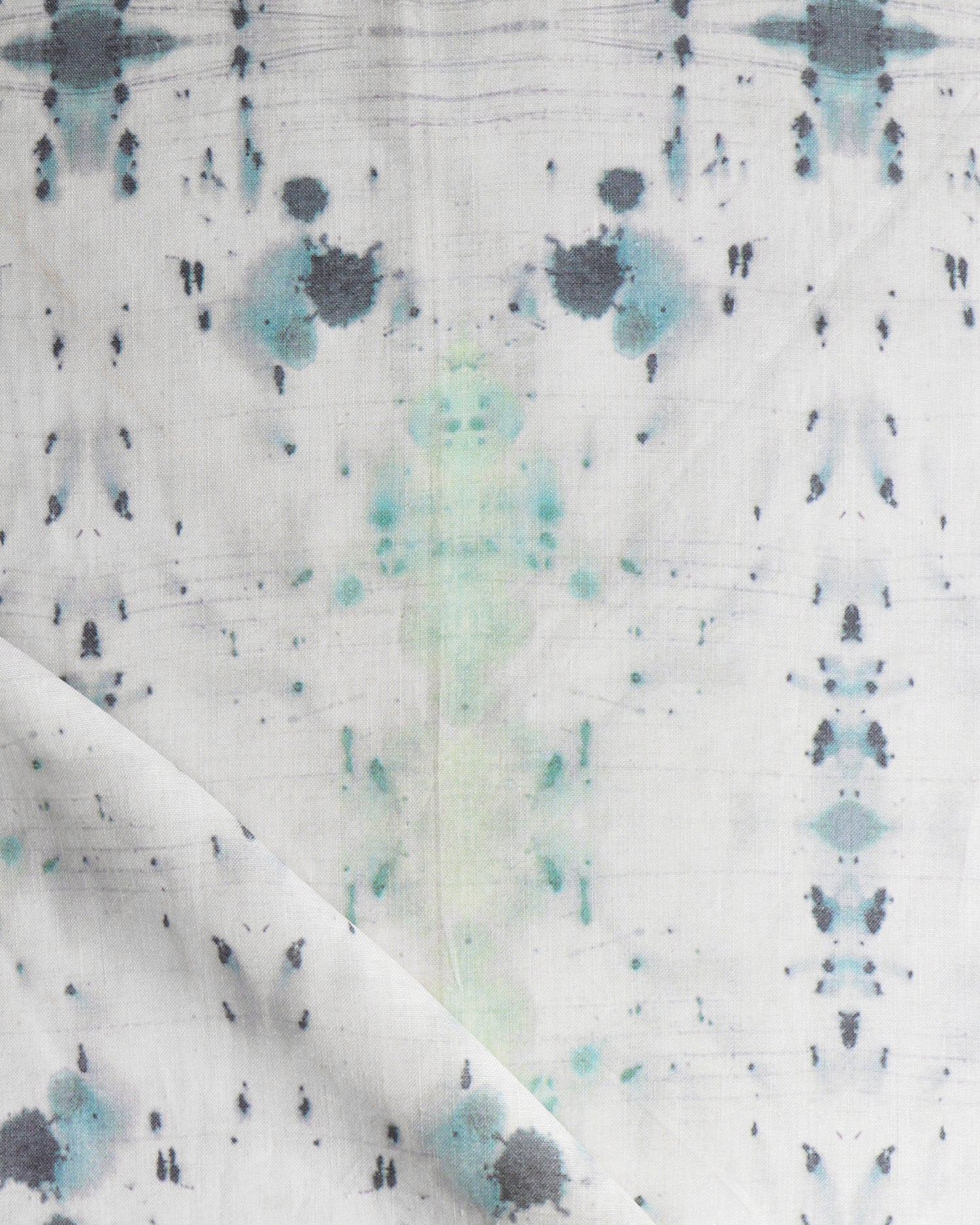 Detail of draped fabric in a watercolor ink blot print in gray and green on a cream field.