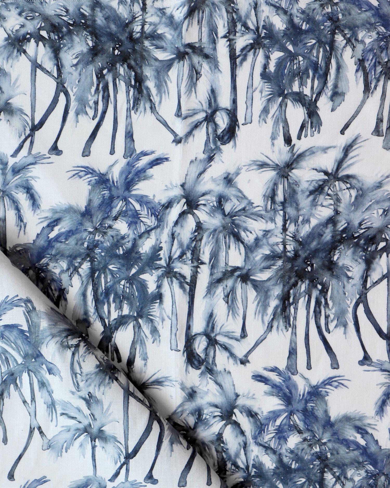 Detail of draped fabric in a painterly palm tree stripe print in shades of navy and gray on a white field.