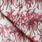 Detail of draped fabric in a painterly palm tree stripe print in shades of pink and red on a white field.