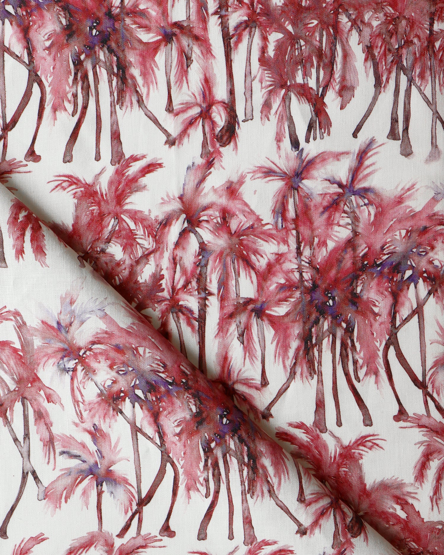 Detail of draped fabric in a painterly palm tree stripe print in shades of pink and red on a white field.