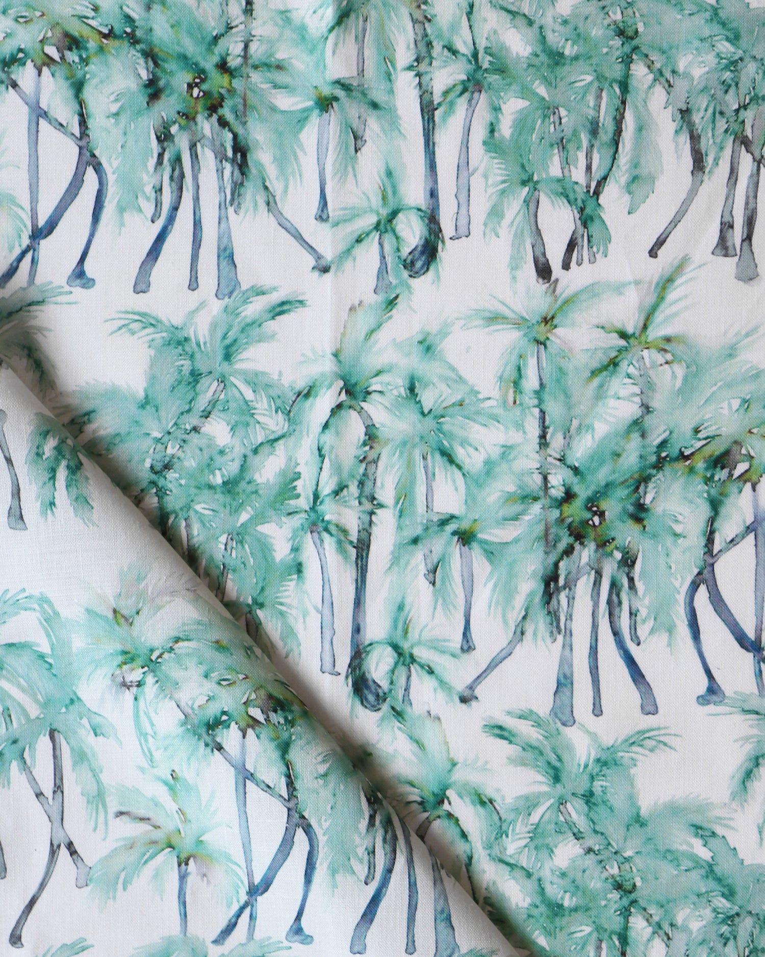 Detail of draped fabric in a painterly palm tree stripe print in shades of green and gray on a white field.