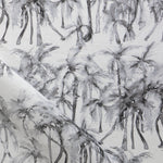 Detail of draped fabric in a painterly palm tree stripe print in shades of gray on a white field.
