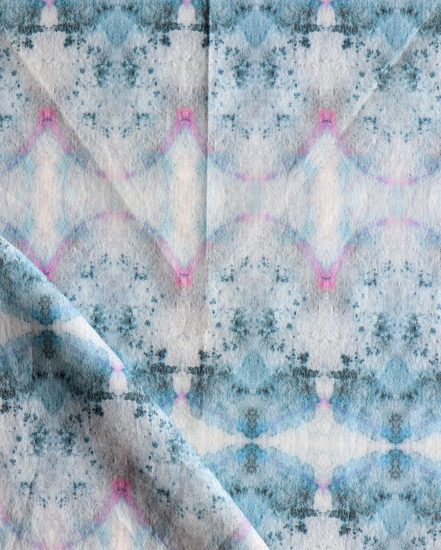 Detail of draped fabric in a watercolor ink blot pattern in shades of gray, blue and pink.