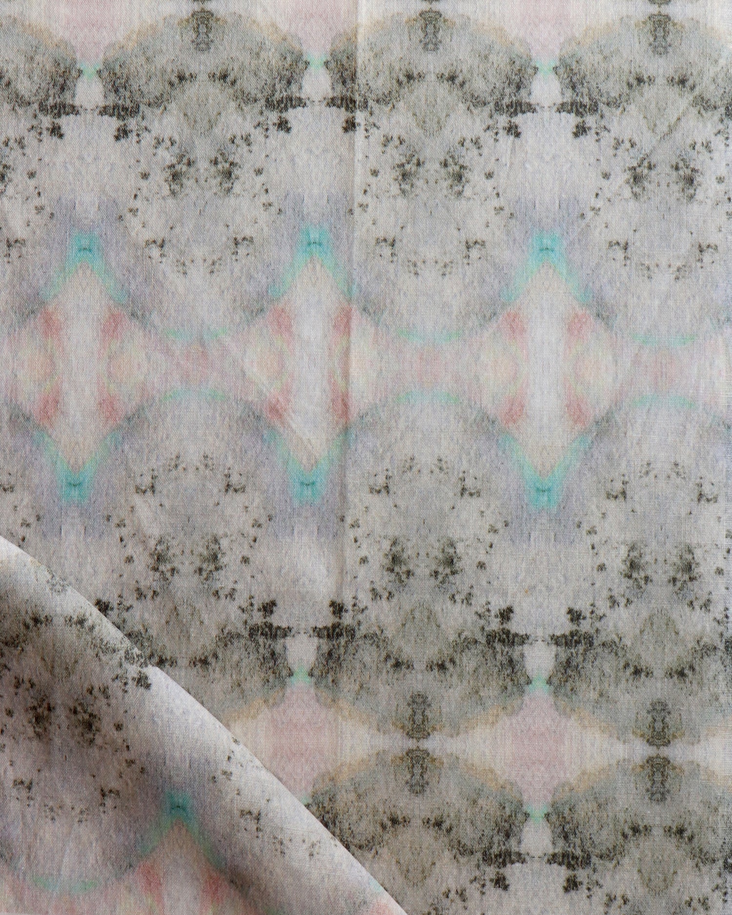 Detail of draped fabric in a watercolor ink blot pattern in shades of tan, turquoise and pink.