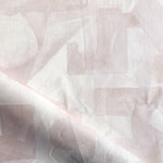 Draped fabric in a geometric puzzle piece watercolor pattern in pastel pink. 