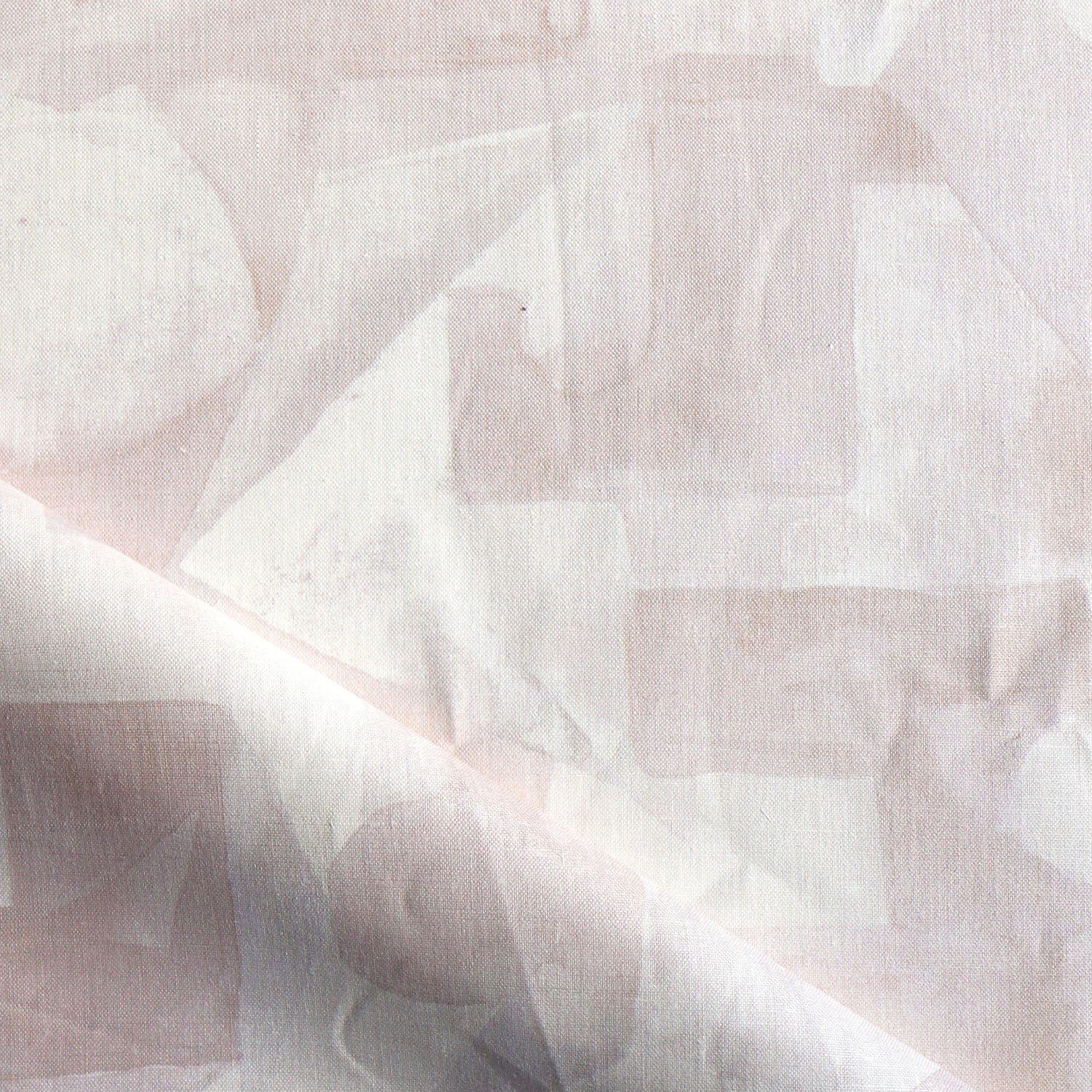 Draped fabric in a geometric puzzle piece watercolor pattern in pastel pink. 