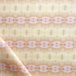 Detail of draped fabric in a gridded paint splatter print in shades of pink, orange, yellow and white.