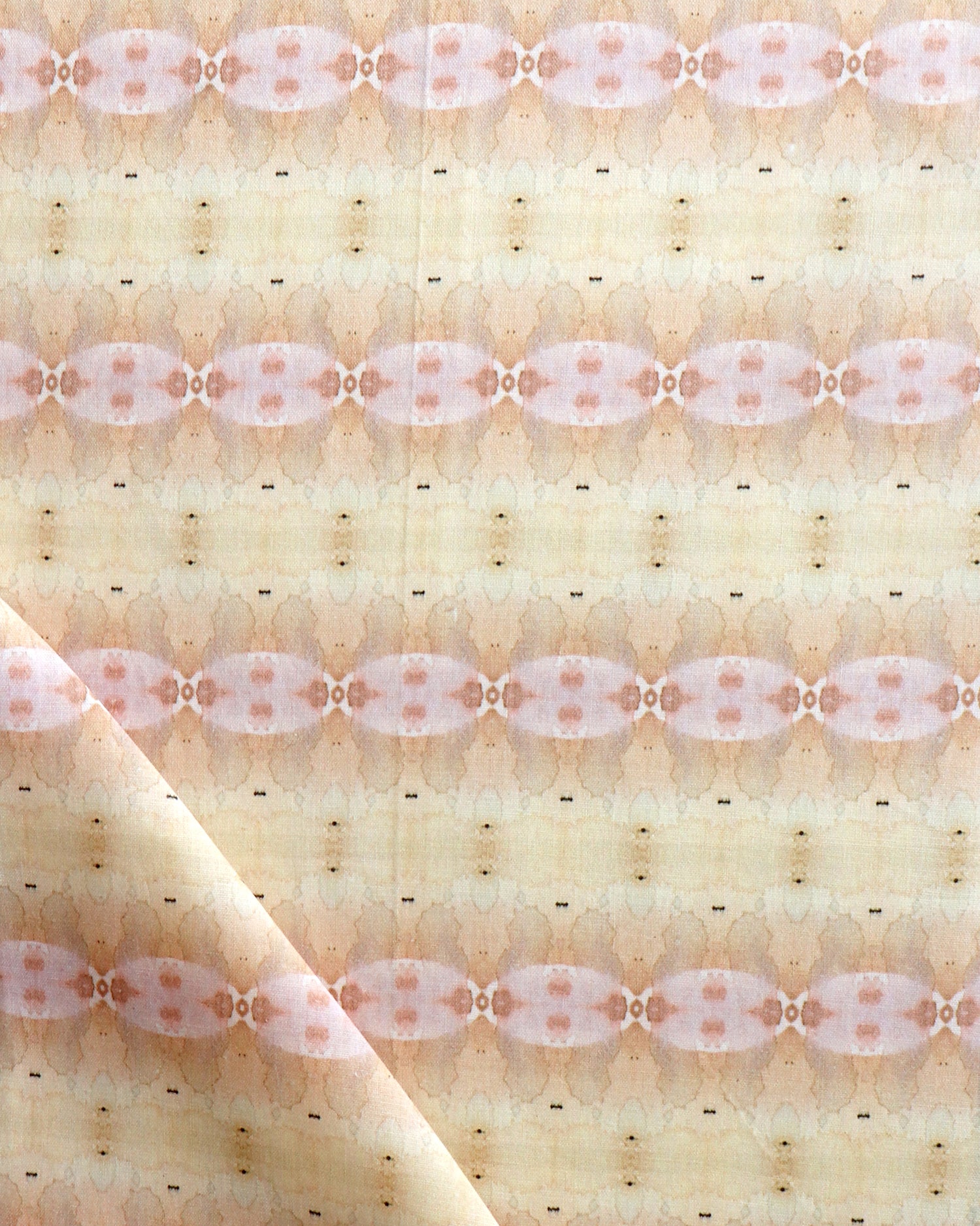 Detail of draped fabric in a gridded paint splatter print in shades of pink, orange, yellow and white.