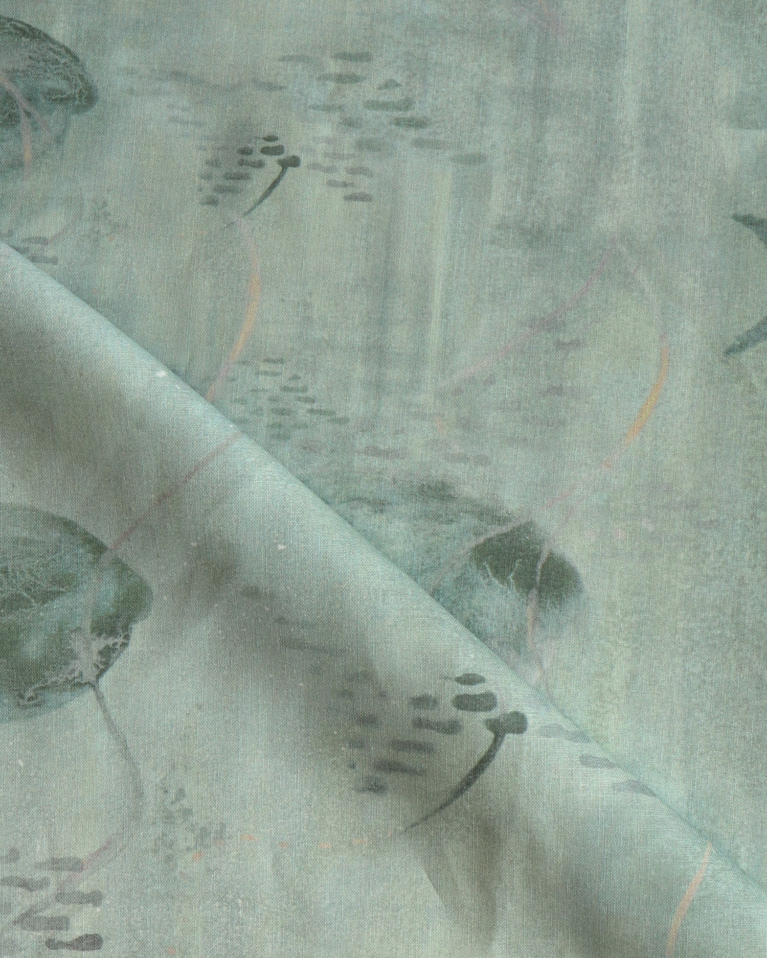 Draped fabric in an watercolor oceanic fish pattern in sage green. 