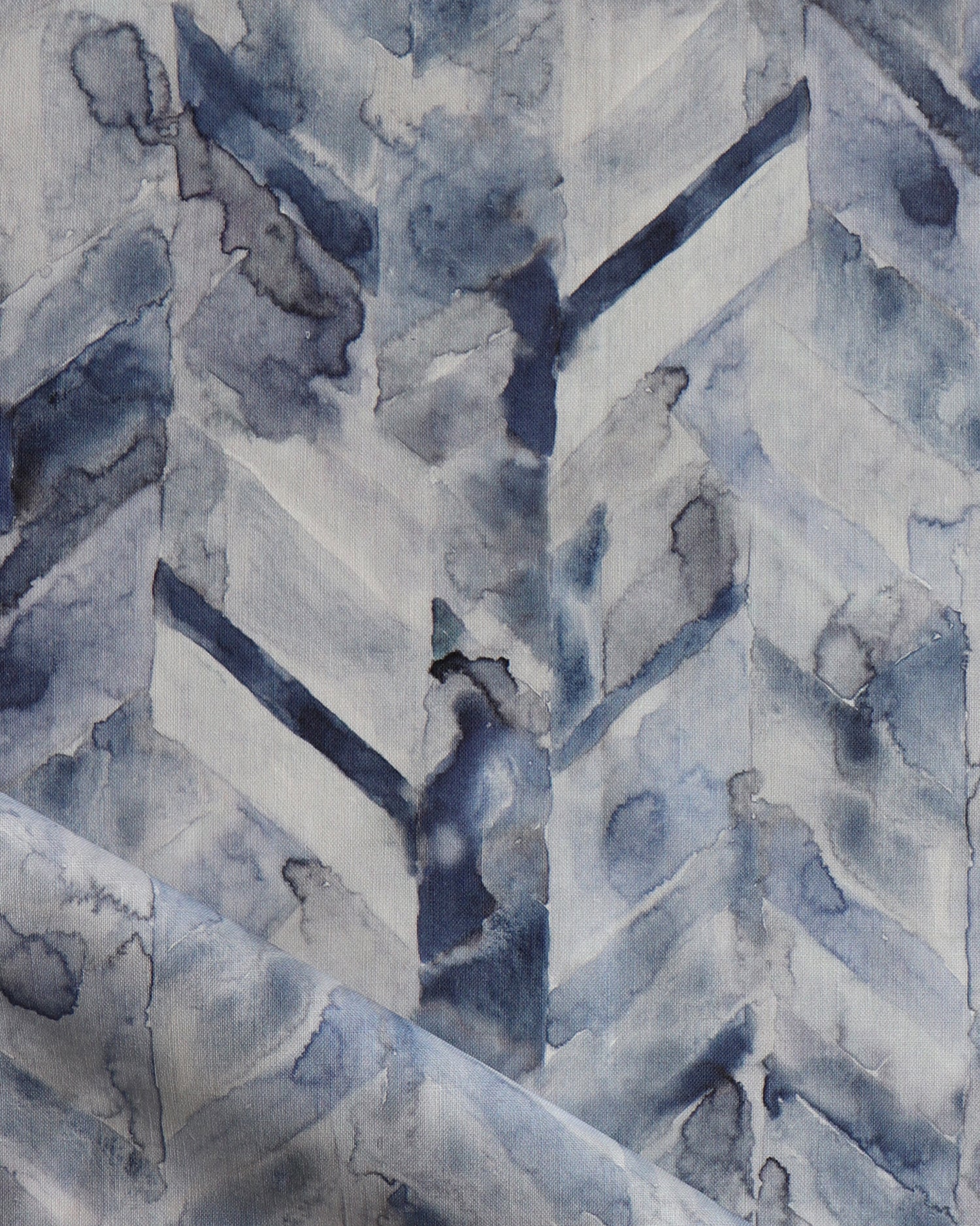 Detail of draped fabric in a painterly herringbone print in shades of blue and gray.