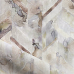 Detail of draped fabric in a painterly herringbone print in shades of gray, tan and cream.