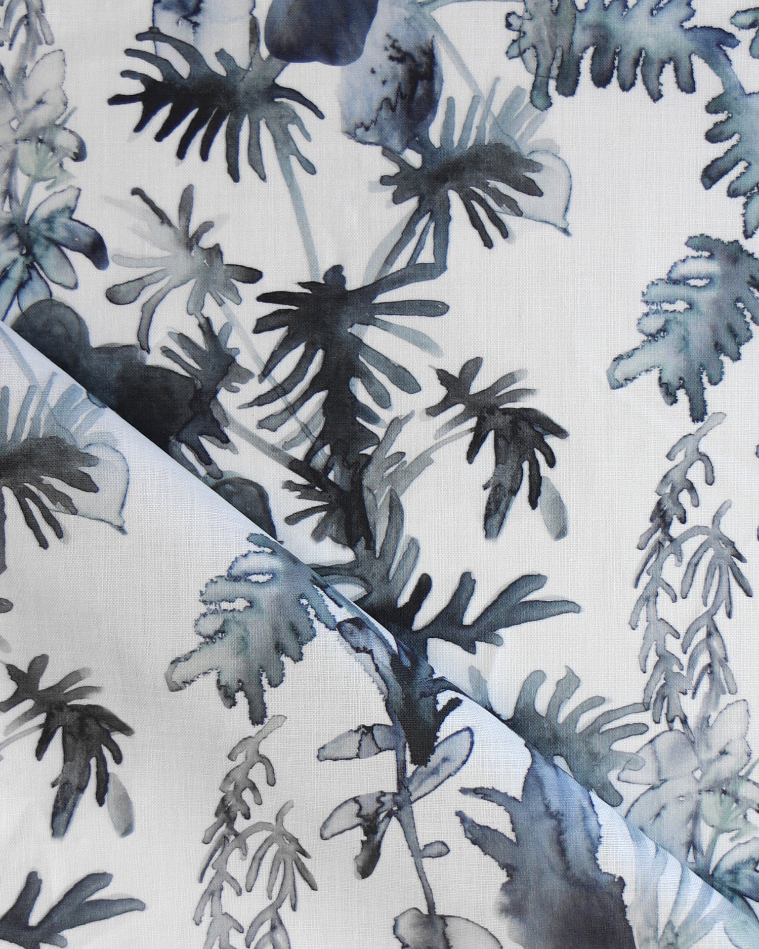 Draped fabric in an watercolor palm frond pattern in shades of dark blue. 