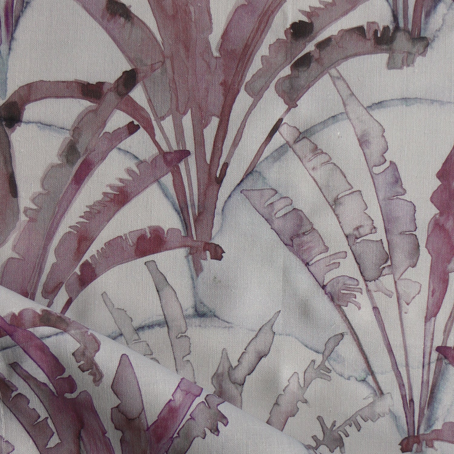 Detail of draped fabric in a painterly palm tree pattern in shades of purple and navy on a gray field.