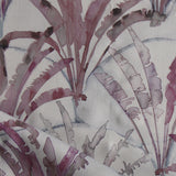 Detail of draped fabric in a painterly palm tree pattern in shades of purple and navy on a gray field.