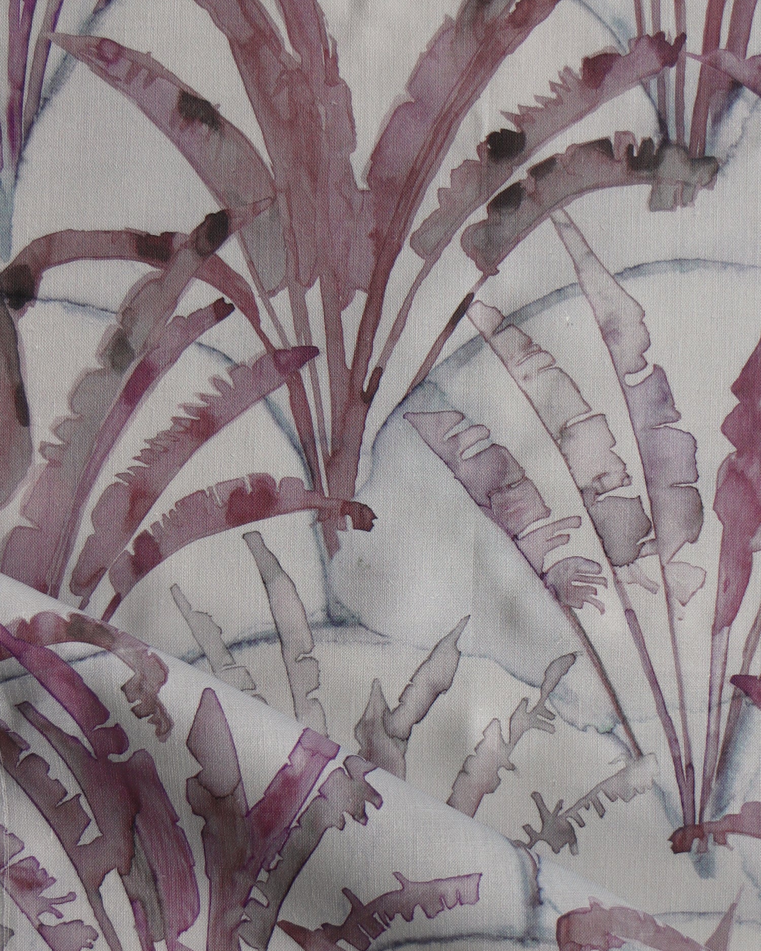 Detail of draped fabric in a painterly palm tree pattern in shades of purple and navy on a gray field.