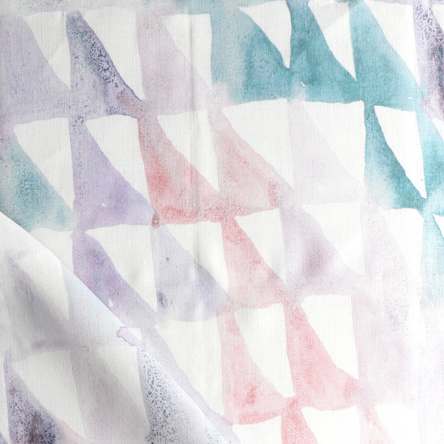 Detail of draped fabric in a painterly check pattern in shades of coral, purple, green and white.