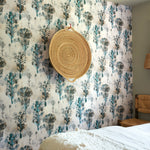Bedroom scene against a watercolor tree print in shades of tan and gray on a blue field.