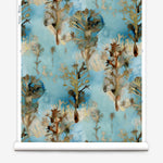 Wallpaper roll in a watercolor tree print in shades of tan and gray on a blue field.