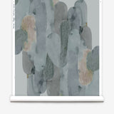 Wallpaper roll in watercolor elongated pill pattern in moody blues and taupe on a white field.