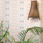 Wallpaper install in repeating ink blot print in shades of purple framed by a plant and hanging basket.