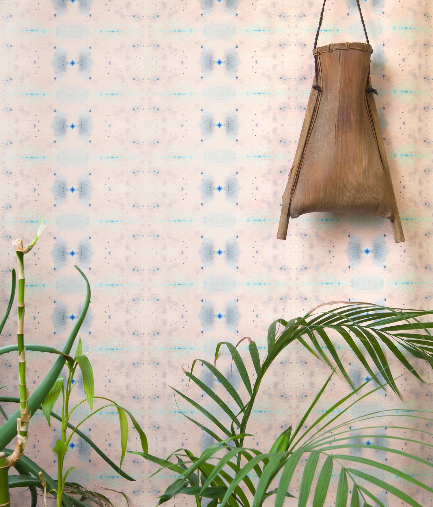 Wallpaper install in repeating ink blot print in shades of purple framed by a plant and hanging basket.