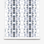 Wallpaper roll in a watercolor ikat stripe print in shades of blue and black on a white field.