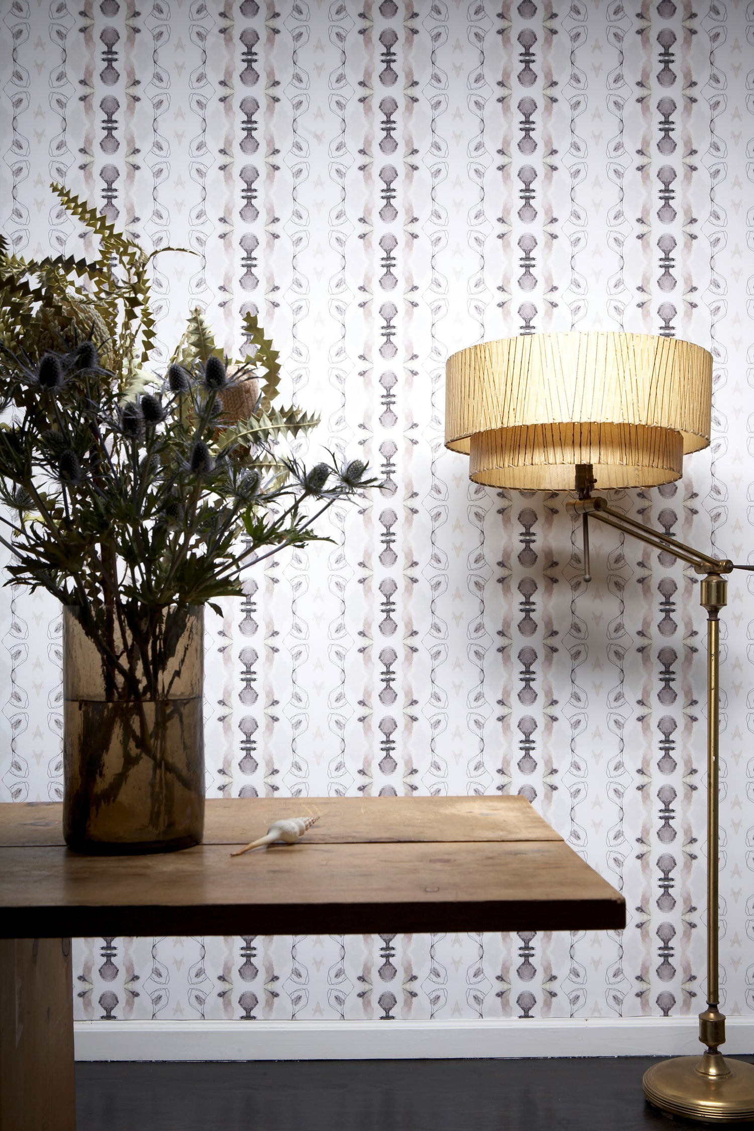 Wallpaper install in a watercolor ikat stripe print in shades of blue and black on a white field, with a floor lamp and wooden diting table. 