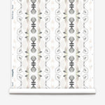 Wallpaper roll in a watercolor ikat stripe print in shades of cream, pink and gray on a white field.