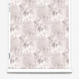 Wallpaper roll in a painterly tree print in light pink and purple on a cream field.
