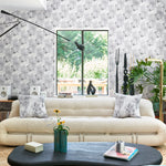 Airy living room scene with modern furniture with wallpaper a in a painterly tree print in gray.