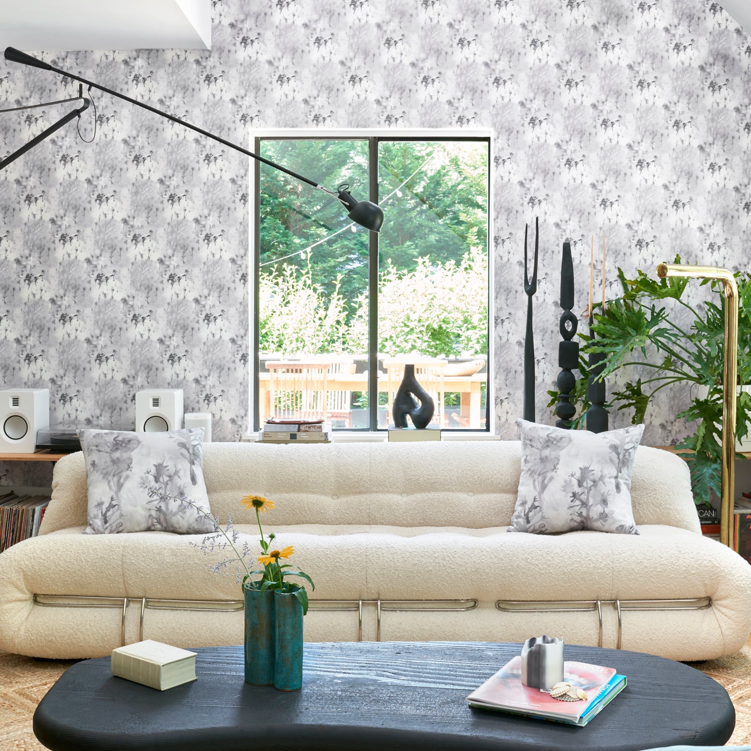 Airy living room scene with modern furniture with wallpaper a in a painterly tree print in gray.