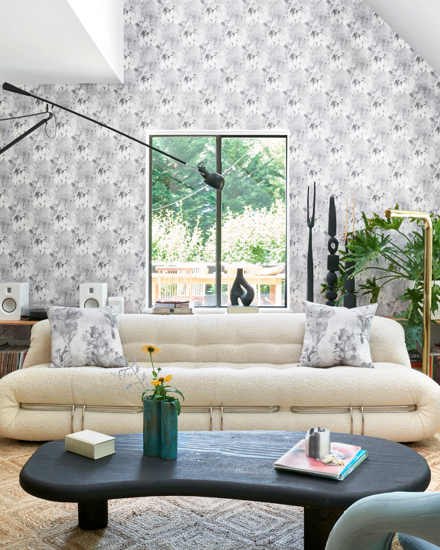Airy living room scene with modern furniture with wallpaper a in a painterly tree print in gray.