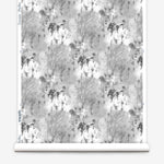 Wallpaper roll in a painterly tree print in gray and charcoal on a white field.