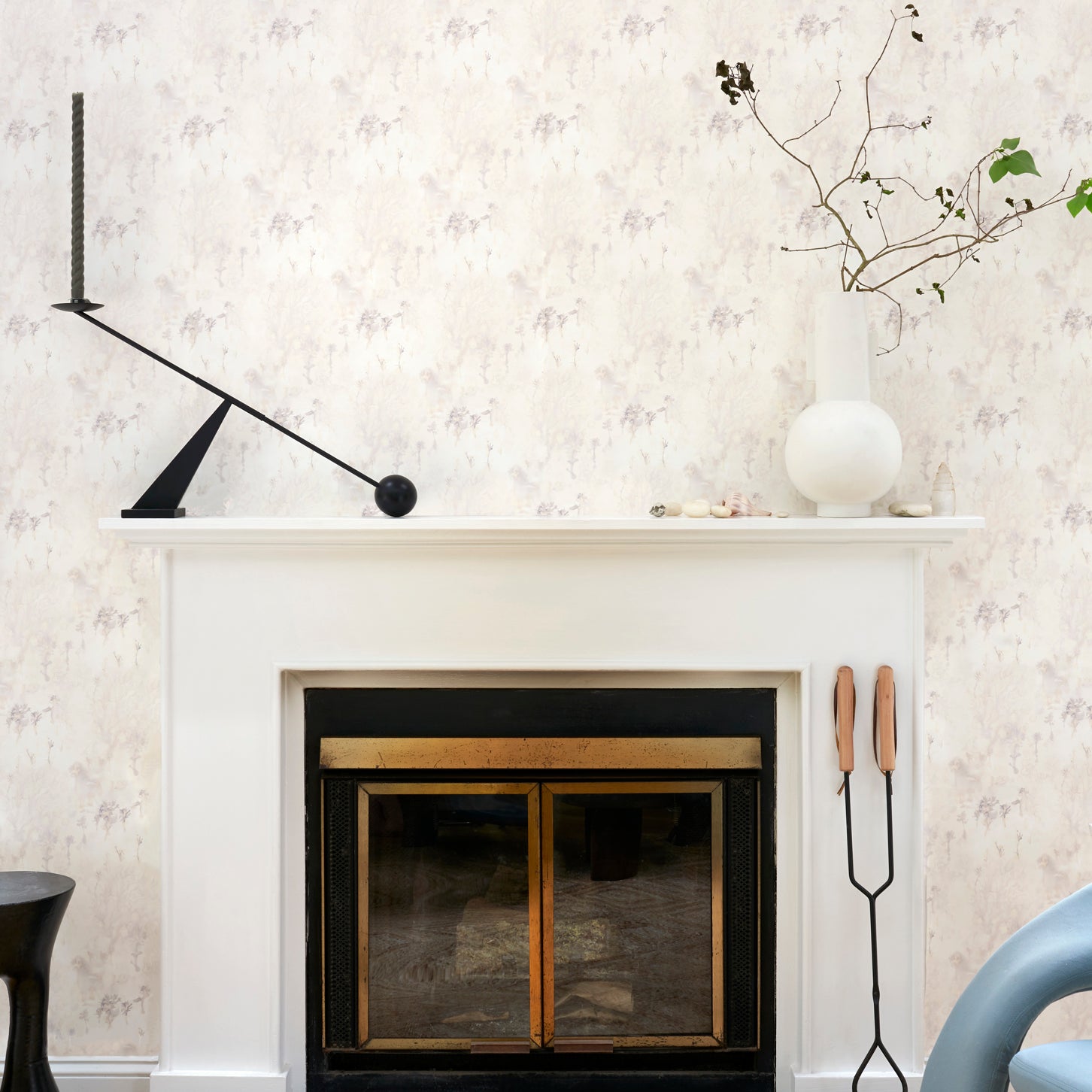 White fireplace hearth surrounded by in a painterly tree print in gray and tan, along side a chocolate lab. 