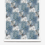 Wallpaper roll in a painterly tree print in blue, gray and tan on a white field.