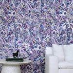White couch and marble side table against wallpaper in abstract brushstroke design in shades of purple and black accents. 