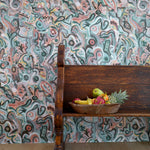 Wooden bench against wallpaper in abstract brushstroke design in shades of teal, rust brown and black accents. 