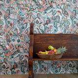 Wooden bench against wallpaper in abstract brushstroke design in shades of teal, rust brown and black accents. 