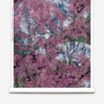 Wallpapper roll in a painterly tree print in purple, green and brown.