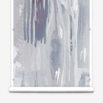 Wallpaper mural roll in a watercolor paint print in shades of purple and gray on a cream field.