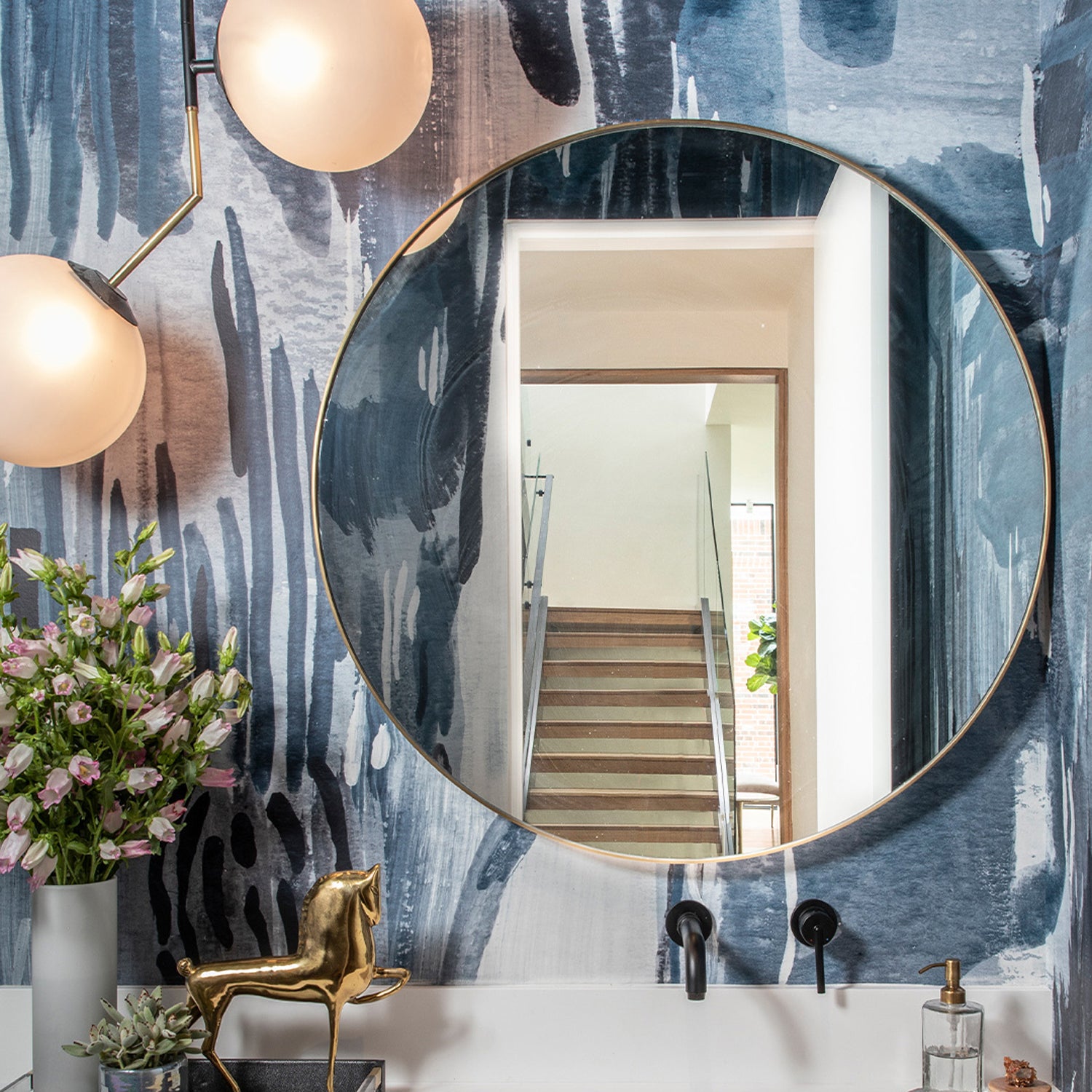 Powder room sink and mirroy aginsta a watercolor mural in dark blue. 