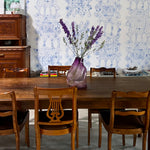 Dining room with wooden table and chairs against a decorative wall.