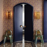 Retro foyer with terrazo floors wallpapered in an undulating abstract watercolor motif in purple, taupe, yellow and charcoal. 