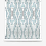 Wallpaper roll in a watercolor diamond print in shades of gray and blue on a cream field.