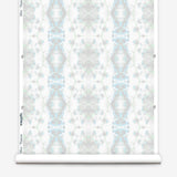Partially unrolled wallpaper yardage in a painterly gometric stripe in gray, blue and green on a white field.